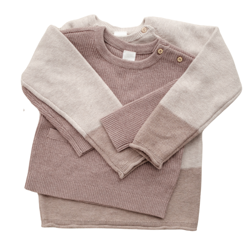 Folded pink sweater with beige collar on a white background
