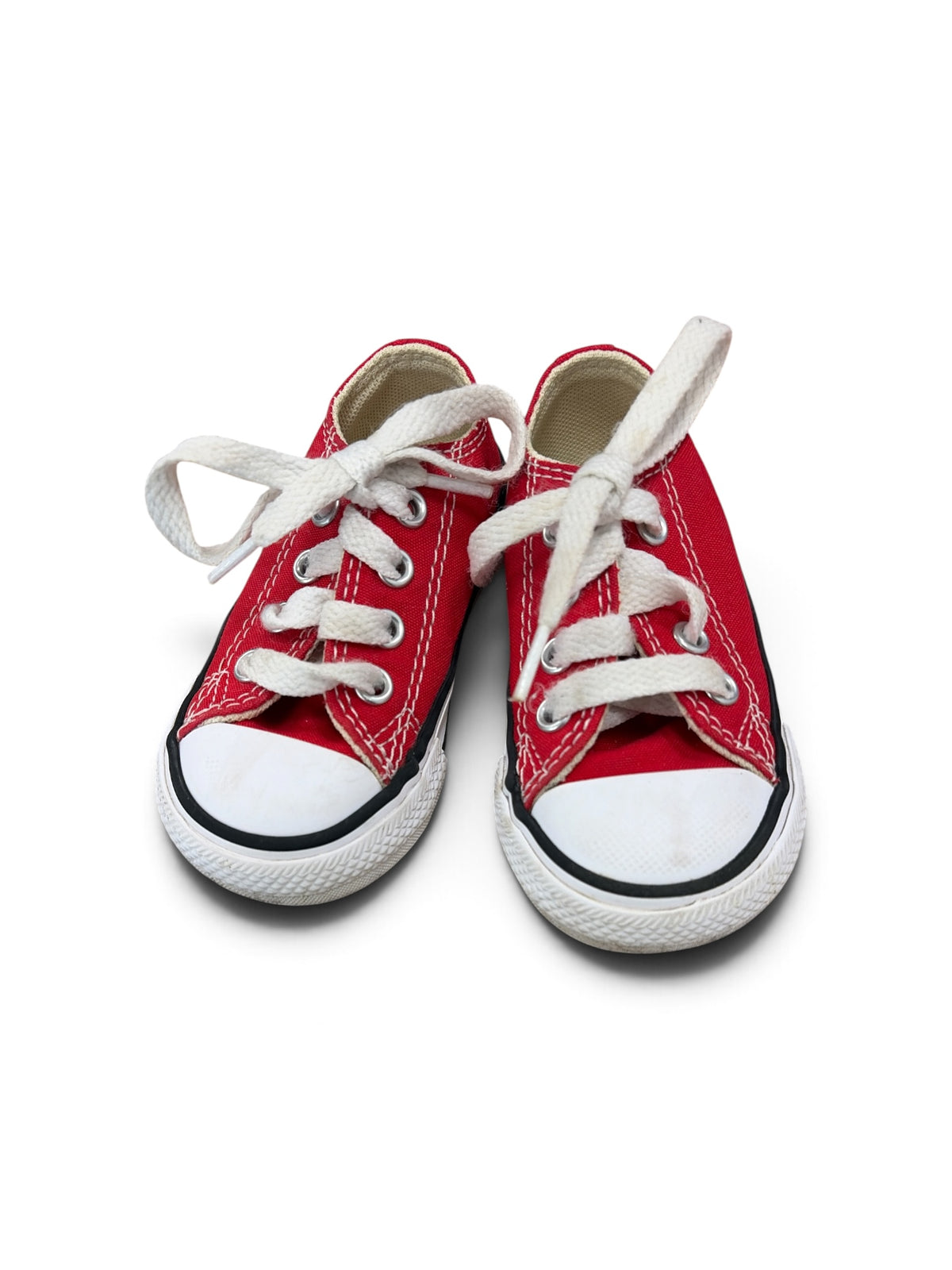 Pair of red canvas Converse low-top sneakers for toddlers with white laces and rubber toe caps.