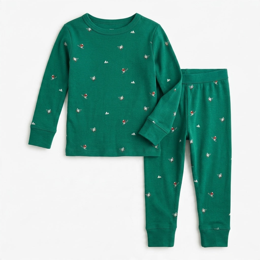 Toddler green long-sleeve pajama set with a festive skier and mountain print in soft cotton fabric.